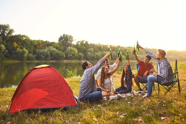 Young people drink, eat and clink glasses at a picnic - Foto, Bild