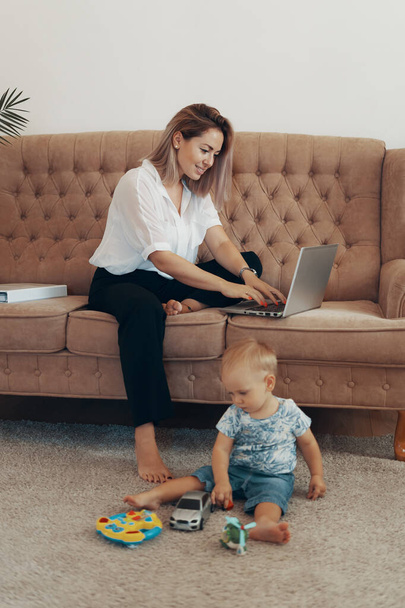 Mooie zakenvrouw die thuis werkt. Multi-tasking, freelance en moederschap concept. Loopbaan van werkende moeder - Foto, afbeelding
