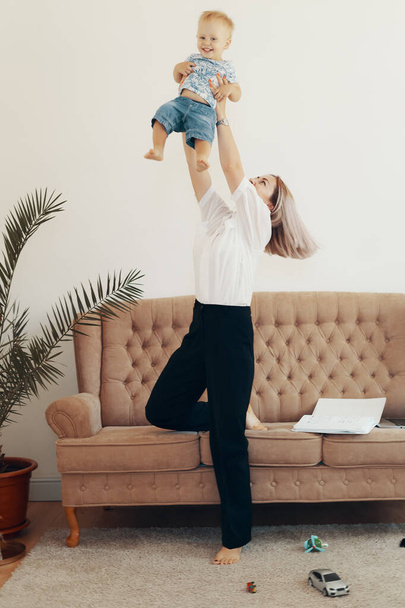 Νεαρή μητέρα με το παιδί της να δουλεύει στο σπίτι. Η μαμά της επιχείρησης κάνει διάλειμμα. Multi-tasking, freelance και έννοια της μητρότητας - Φωτογραφία, εικόνα