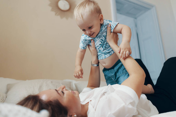 Young mother having fun laughing playing funny active games with cute child son in bedroom at home - Fotoğraf, Görsel