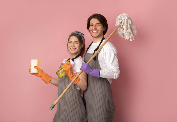 Siivouspalvelu joukkue esiliinat poseeraa yli vaaleanpunainen tausta studiossa
 - Valokuva, kuva