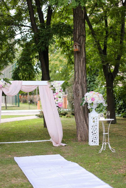 Arco de boda, decorado con rosas y sillas en el parque
. - Foto, imagen
