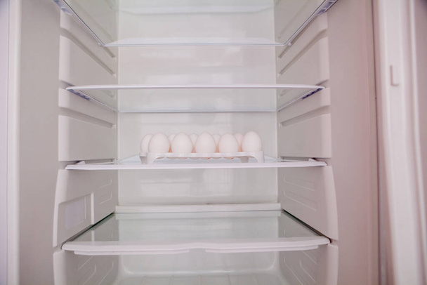 Chicken eggs standing on the empty shelf of the refrigerator in the egg tray. - Foto, immagini