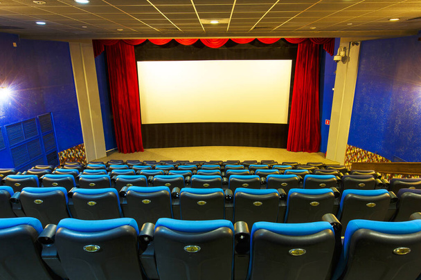 Empty hall in the cinema. Empty blue seats in the cinema on the background of a white movie screen. - Photo, Image