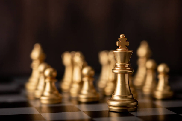 gold king is the leader standing front of chess on board in game - Photo, Image