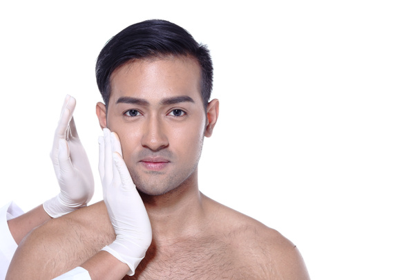 アジア人男性は、整形手術前に目、鼻、眉、額、頬、顎をチェックしたい、看護師のゴム手袋で触れる、テキストロゴのためのスタジオ照明白い背景コピースペース - 写真・画像