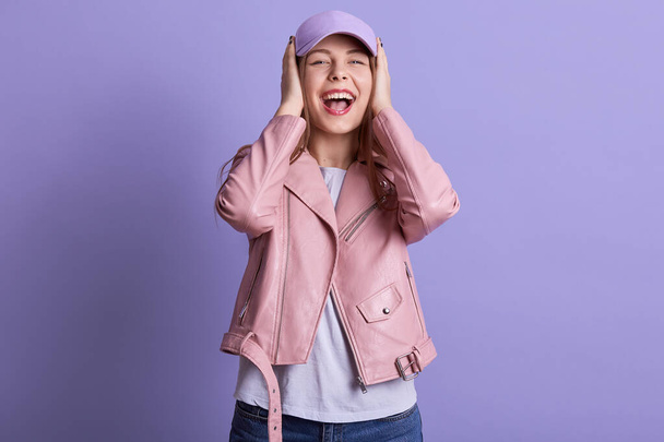 Picture of beautiful charming sweet female opening mouth widely, laughing, being in high spirits, covering her ears with both hands, no hearing, wearing casual clothes. People and emotions concept. - Photo, Image