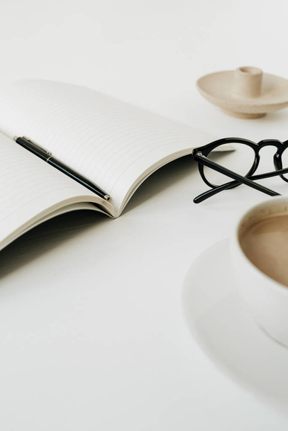 Moderner Schreibtisch im Home Office mit Notizbuch, Tasse Kaffee, Brille auf weißem Hintergrund. Arbeit, Geschäftskonzept. - Foto, Bild