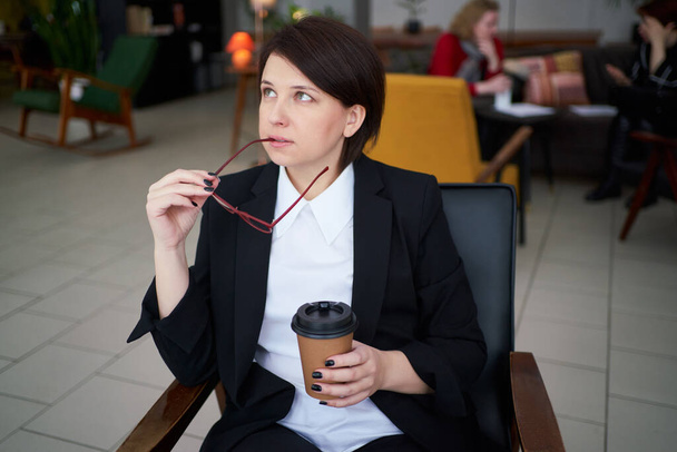 Young business woman relaxing, listening music and drinking coffee during break from work - Photo, Image
