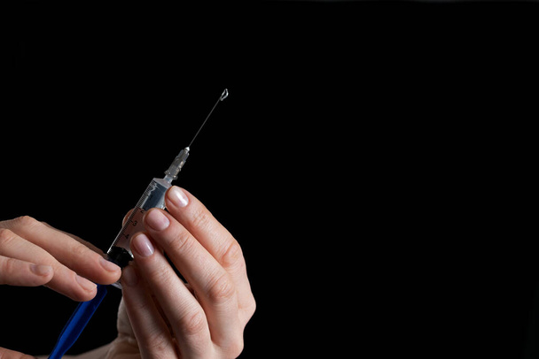 syringe for injection with medicine in hands on a black background - Foto, Imagen
