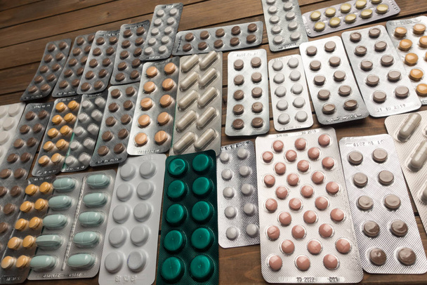 Detailní záběr různých pilulek na stole s tabletami, koncept farmaceutického průmyslu - Fotografie, Obrázek