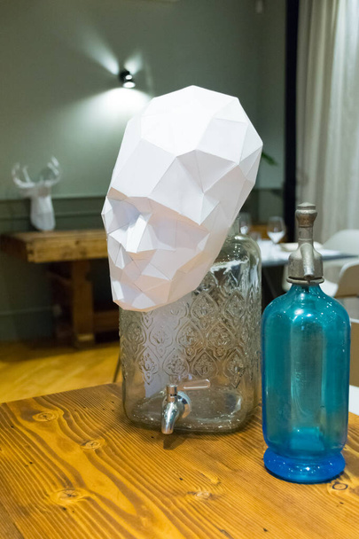 Bottle of seltzer twenty years and face of man in paper handmade ornaments as a wooden table - Photo, Image