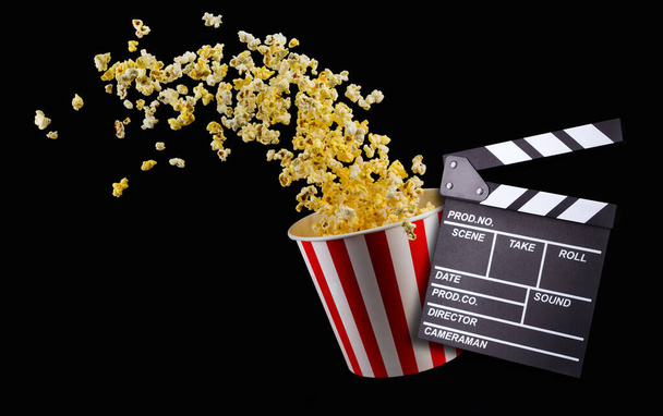 Flying popcorn from striped bucket isolated on black background - Zdjęcie, obraz