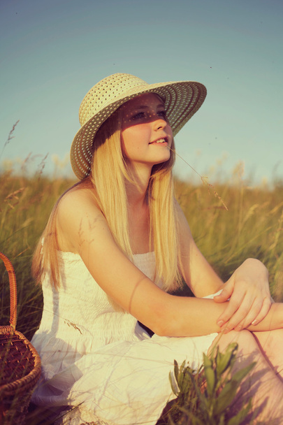 mladá dívka v slaměný klobouk sedí v poli - Fotografie, Obrázek