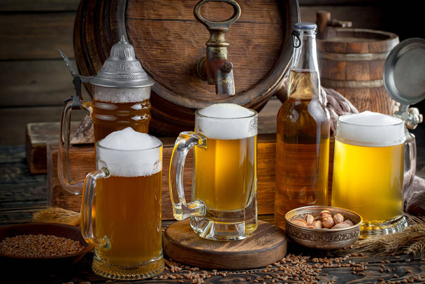 Легкое пиво в стакане на столе в композиции с аксессуарами на старом фоне
 - Фото, изображение