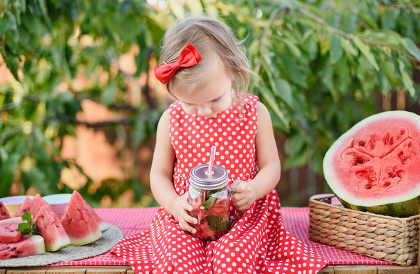 Limonadenstand vorhanden. Entzückendes kleines Mädchen beim Versuch, Limonade zu verkaufen. Wassermelonen-Limonade mit Eis und Minze als sommerliches Erfrischungsgetränk im Glas. Kaltgetränke mit Früchten. Kind trinkt Limonade im Glas - Foto, Bild