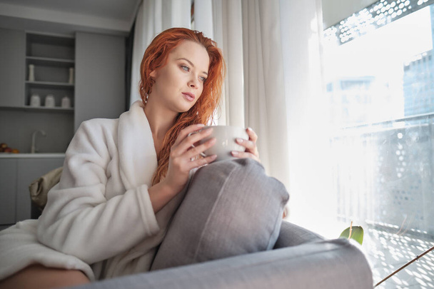 stayhome concept,  attractivewoman sitting in bed , holding cup of black coffee, enjoying peaceful calm weekend vacation morning time alone in bedroom at home or hotel. - 写真・画像