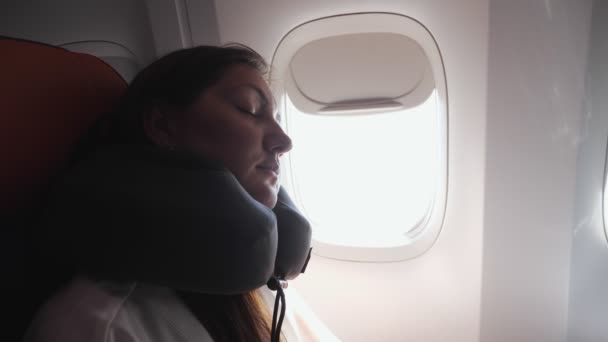 fiatal nő alszik nyakpárna ellen porthole közelkép - Felvétel, videó