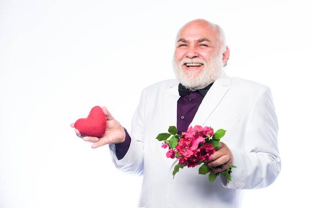 True love. happy mature man hold flowers and heart. love and romance. Health care treatment. problems with heart. bearded businessman. heart failure. anniversary and valentines day. donor transplant - Foto, immagini
