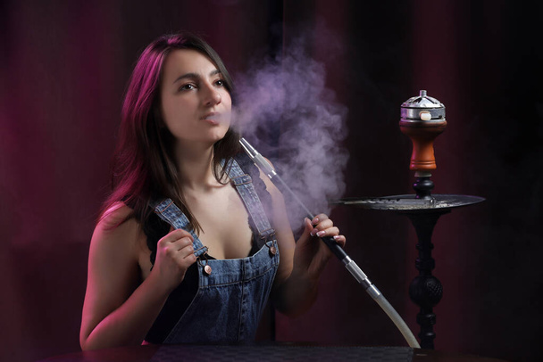 Porträt einer Frau, die in einem Aufenthaltsraum Wasserpfeife raucht - Foto, Bild