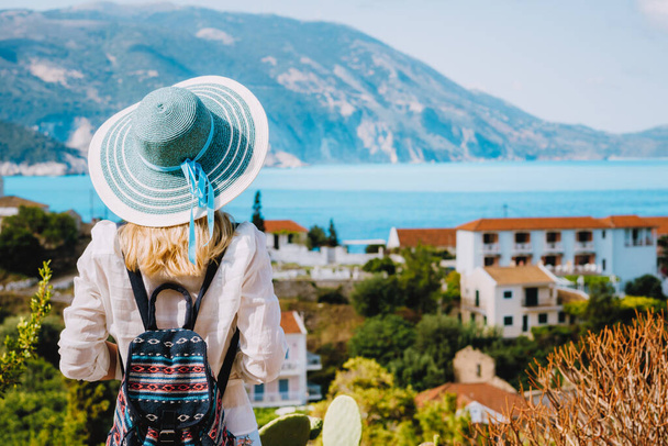 Tourist female with blue sun hat enjoying greek cute and vivid colored Assos town on Kefalonia island, Greece - Foto, afbeelding