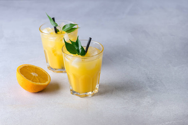 Tasty and Refreshing Orange Juice in Glasses with Black Straws on Light Gray Background Fresh Ripe Oranges Vitamin or Detox Drink Copy Space - Fotó, kép