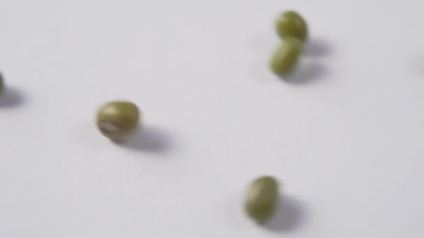 Mung bean roll and stop on the white surface of the plate. Slow motion. Macro - Felvétel, videó