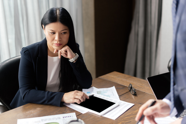 cropped view of businessman and pensive asian businesswoman during business meeting  - Photo, Image