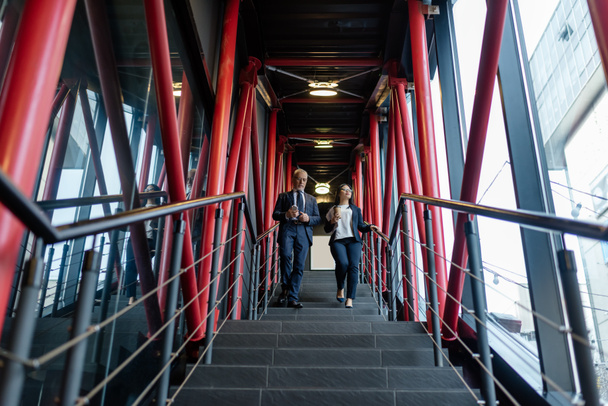 nízký úhel pohledu na podnikatele a asijské podnikatelky chůze na schodech  - Fotografie, Obrázek