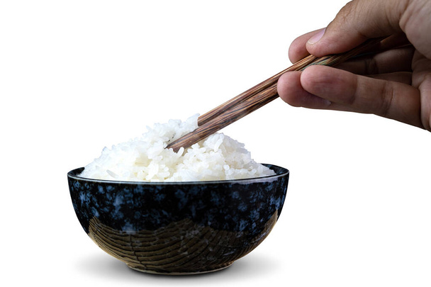 Приготований рис жасмину в керамічних чашках і паличках, що тримають гарячий рис жасмину рукою. ізольовані на білому тлі. з відсічними контурами
. - Фото, зображення