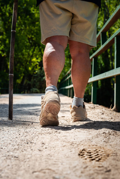 Yürüyüş botlu kadın bacakları yolda ayak izi bırakıyor. - Fotoğraf, Görsel