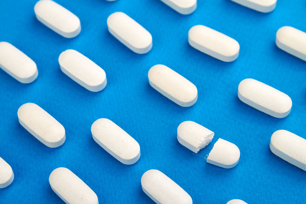 Row of White pills on blue background. - Foto, Bild