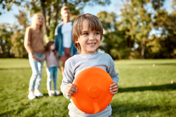 Weekend samen. Kleine jongen speelt frisbee in het park op een zonnige dag - Foto, afbeelding