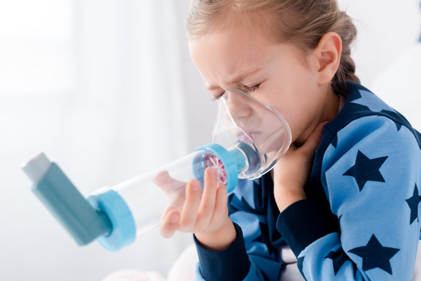 άρρωστο παιδί με κλειστά μάτια χρησιμοποιώντας αναπνευστήρα με αποστάτη - Φωτογραφία, εικόνα