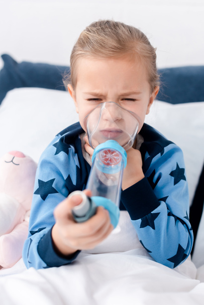selective focus of asthmatic kid using inhaler with spacer - Photo, Image