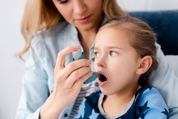caring mother holding inhaler near asthmatic daughter  - Fotografie, Obrázek