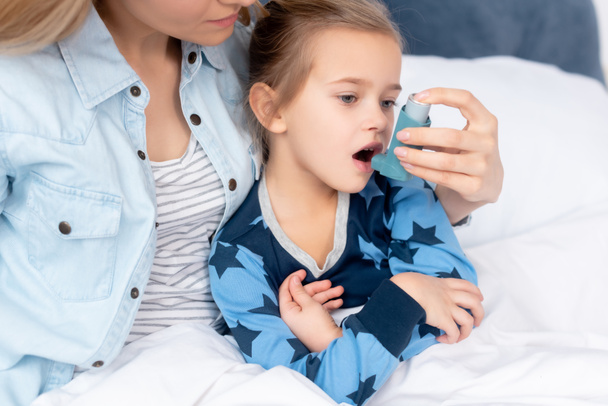caring mother holding inhaler with spacer near sick daughter  - Photo, Image