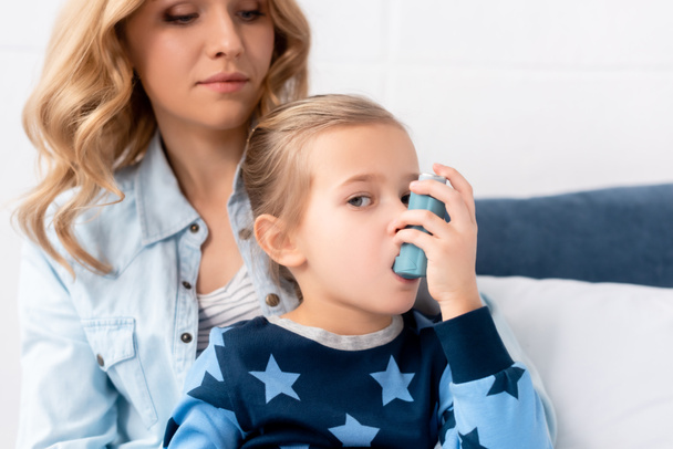 caring mother looking at sick daughter using inhaler - Fotoğraf, Görsel