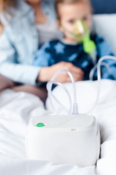 喘息の子供と母親の近くの圧縮機吸入器の選択的な焦点  - 写真・画像