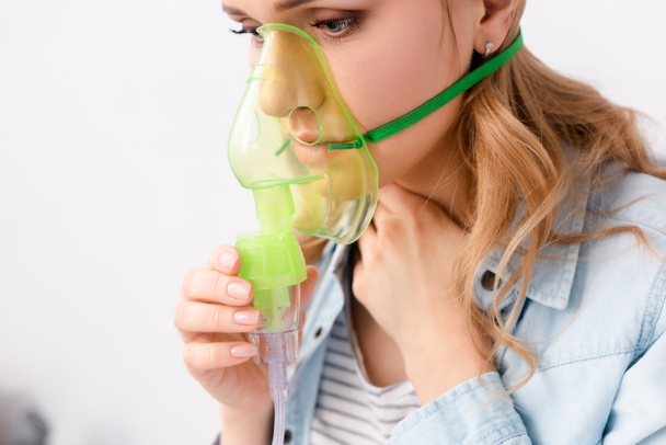 astmatische vrouw met ademhalingsmasker in de buurt van gezicht - Foto, afbeelding