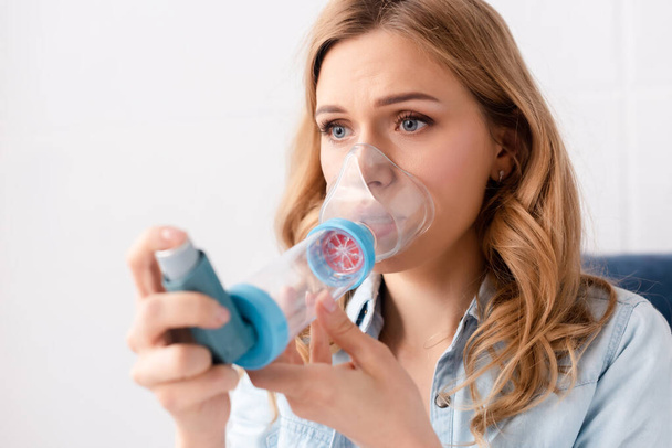 az inhalátort távtartóval használó asztmás nő szelektív fókusza  - Fotó, kép
