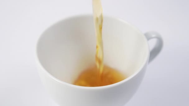 Black tea is pouring into a white cup on the table. Slow motion. Macro shot. - Záběry, video