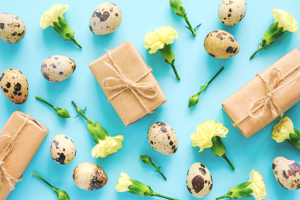 Spring floral and eggs backdrop or wallpaper. Yellow flowers, craft gifts and quail eggs on blue background. Happy Easter, zero waste concept Creative Flat lay Top view Backdrop for your design. - Фото, зображення