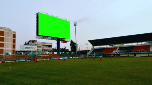 Zeitraffer-Aufnahme der Fußballmannschaft beim Üben im Stadion am Abend bis Sonnenuntergang mit grünem Bildschirm für Chroma-Taste im Hintergrund, das Stadionlicht schaltet sich beim Üben ein und aus: Bangkok, Thailand, Juli 2013 - Filmmaterial, Video