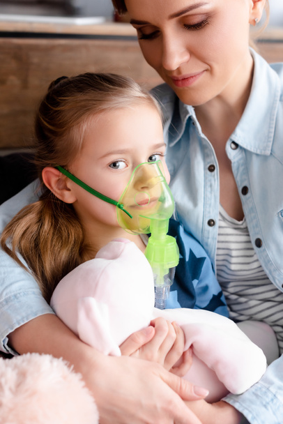asztmás gyerek légzési maszkot használ az anya közelében  - Fotó, kép