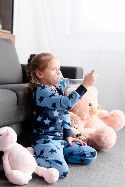ziek kind met behulp van inhalator met afstandsbediening in de buurt van zacht speelgoed - Foto, afbeelding