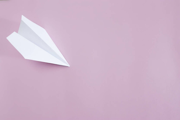 Flat lay white paper plane on pink background. Copy space. - Foto, afbeelding