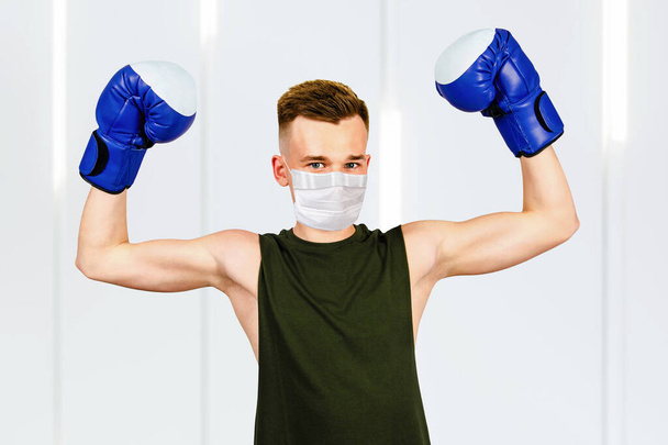 young guy with boxing gloves, wearing a protective face mask prevent virus infection. - Photo, Image