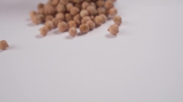 Chickpea or lamb peas are scattered on a table from a white cup. Slow motion. Macro - Metraje, vídeo