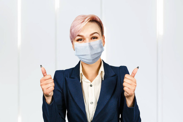 young woman show thumb up, wearing protective face mask prevent virus infection. - Foto, afbeelding